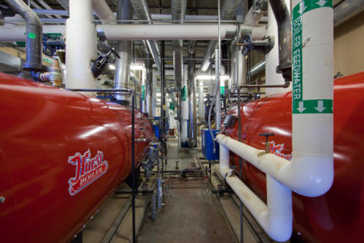 Boiler room with large red tanks and insulated pipes