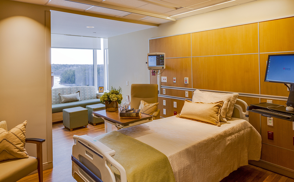 Modern patient room with bed, furniture and medical monitoring equipment