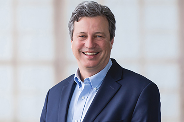 Man smiles while wearing a navy blazer and a blue button-down shirt - Kevin Neumann