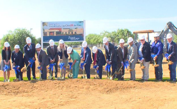 E4H team members with hardhats and shovels standing in a line getting ready to break ground on a medical center