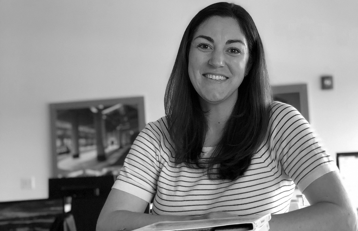 A woman, Lisa Bonnet, smiles while wearing a striped shirt in her office