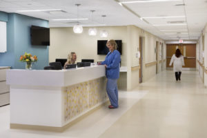 Nurse Station in hospital with receptionist, nurse and doctor walking down hallway
