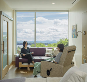 Hospital patient room with two women seated on chair and couch talking