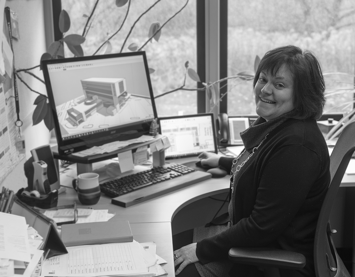Jennifer Arbuckle, a Partner in the Vermont office, sits at her desk and smiles while looking at a design on her computer